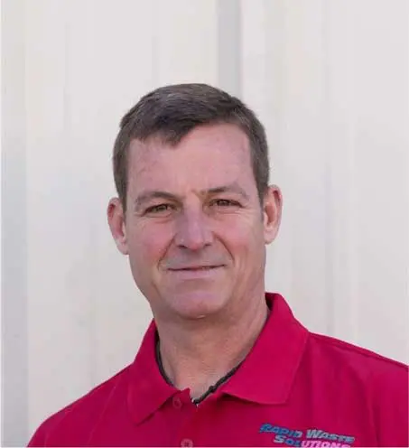 A man in red shirt standing next to white wall.
