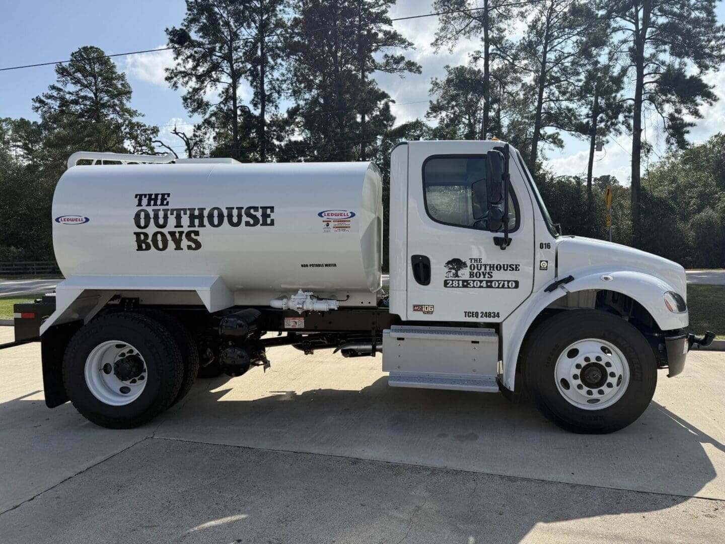 White septic truck labeled "The Outhouse Boys".